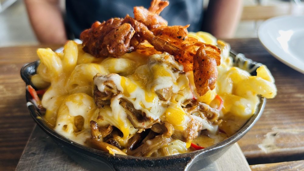 Cheesy macaroni topped with fried chicken displayed in a skillet.