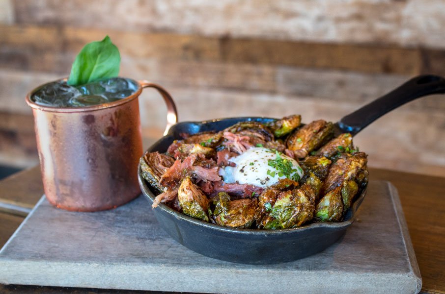 A spread of gourmet dishes including burgers, BBQ, salads, and craft cocktails, perfect for group dining at Private Event Venue Carlsbad.