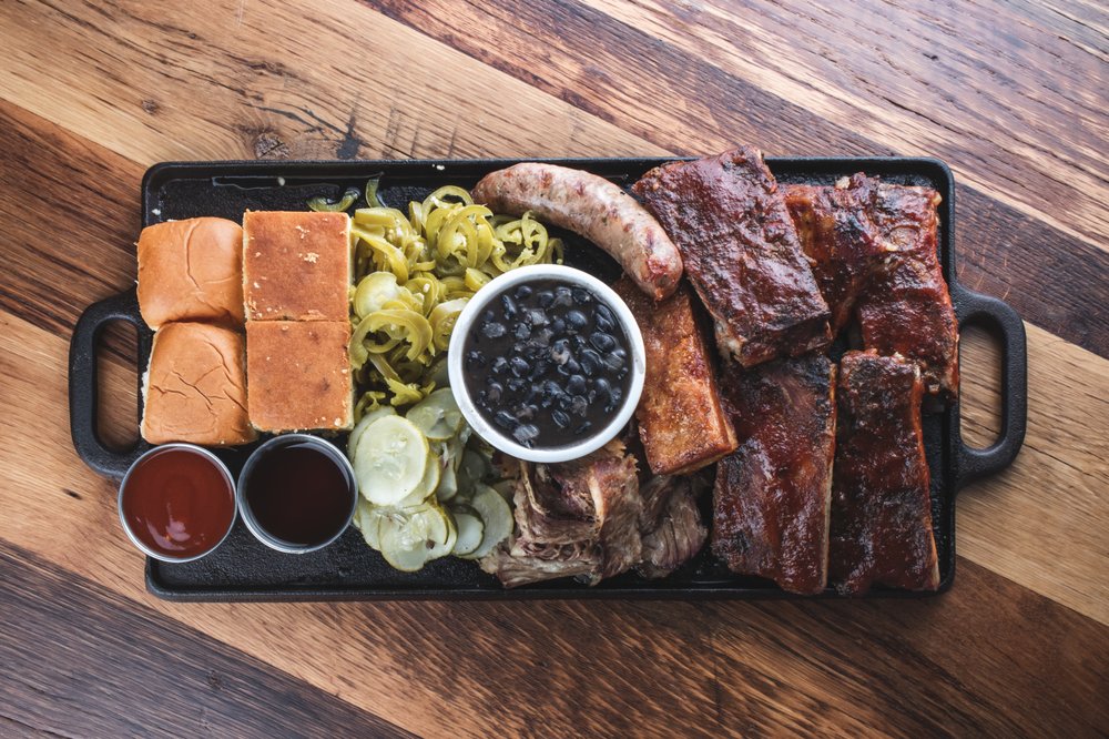 A rustic wooden board featuring grilled sausages with sauerkraut, potato salad, and mustard, an ideal shareable dish at Private Event Venue Carlsbad.